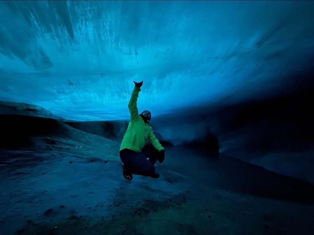Persona dentro de la cueva de hielo del Glaciar Vicinguerra en Ushuaia, tocando el techo de hielo milenario.