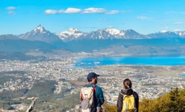 Pareja disfrutando de las vistas panorámicas desde el Monte Susana en Ushuaia, con el Canal Beagle, la ciudad y las montañas de fondo.
