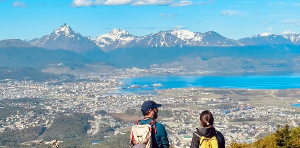 Pareja disfrutando de las vistas panorámicas desde el Monte Susana en Ushuaia, con el Canal Beagle, la ciudad y las montañas de fondo.