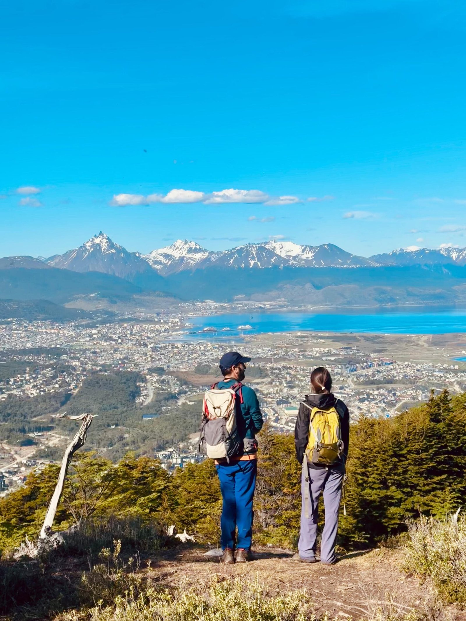 Pareja disfrutando de las vistas panorámicas desde el Monte Susana en Ushuaia, con el Canal Beagle, la ciudad y las montañas de fondo.