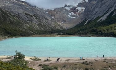 Vista panorámica de la Laguna Esmeralda en Ushuaia, capturada al llegar al final del sendero de trekking, rodeada de montañas y bosques patagónicos.
