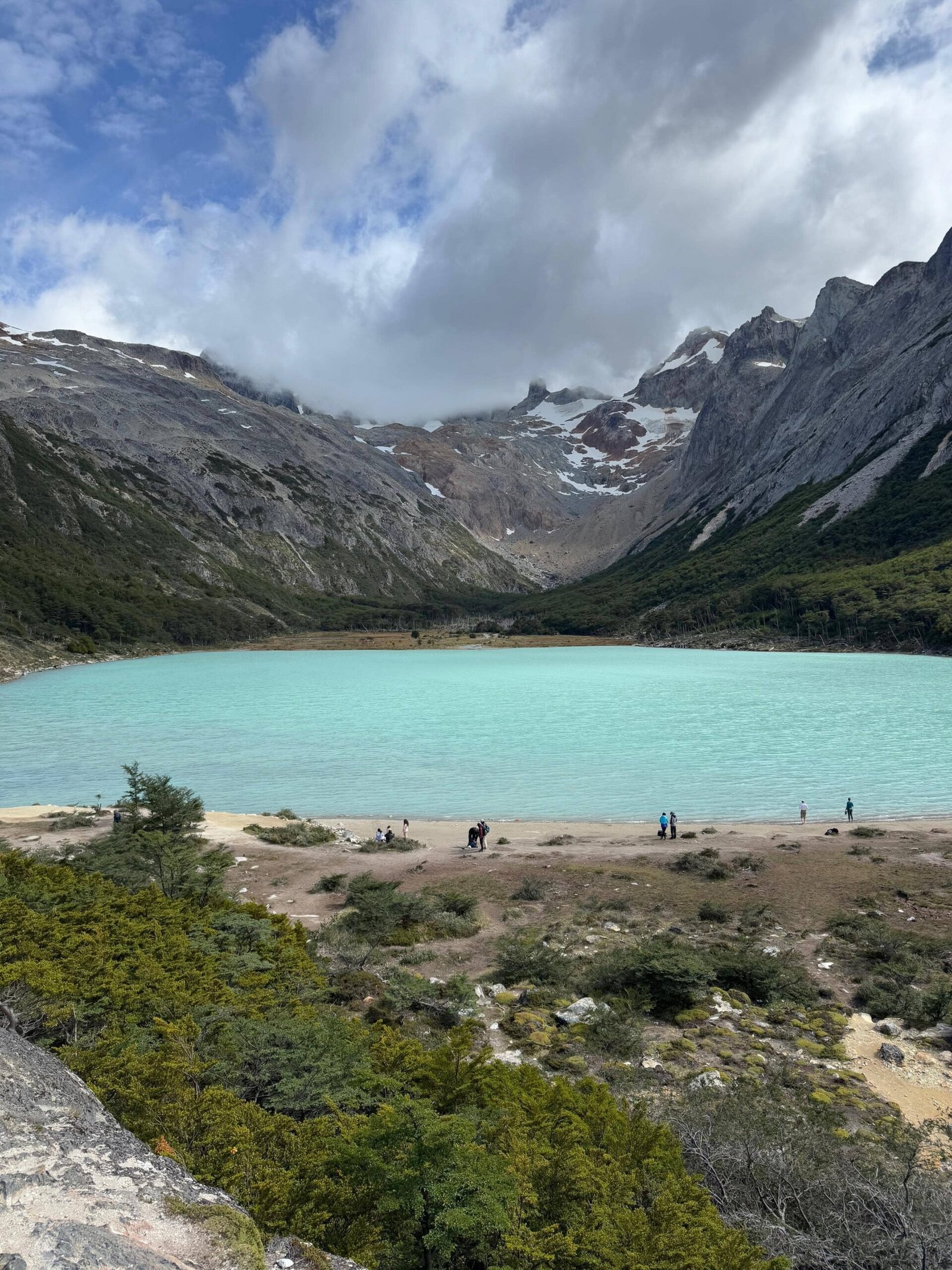Vista panorámica de la Laguna Esmeralda en Ushuaia, capturada al llegar al final del sendero de trekking, rodeada de montañas y bosques patagónicos.