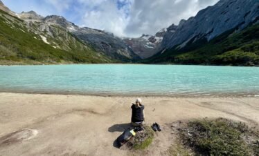 Persona sentada frente a la Laguna Esmeralda en Ushuaia, disfrutando de la tranquilidad y la vista panorámica sin turistas al llegar temprano con XPLOR TURISMO