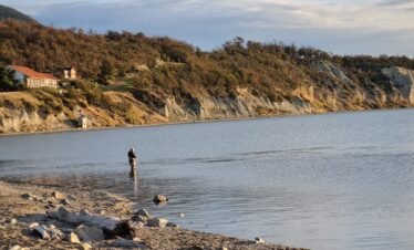 Pescador en la cabecera del Lago Fagnano, Tolhuin, lanzando su línea en busca de truchas en un entorno natural patagónico.