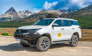Camioneta 4x4 blanca estacionada en el Valle de Tierra Mayor con montañas nevadas al fondo en Tierra del Fuego.