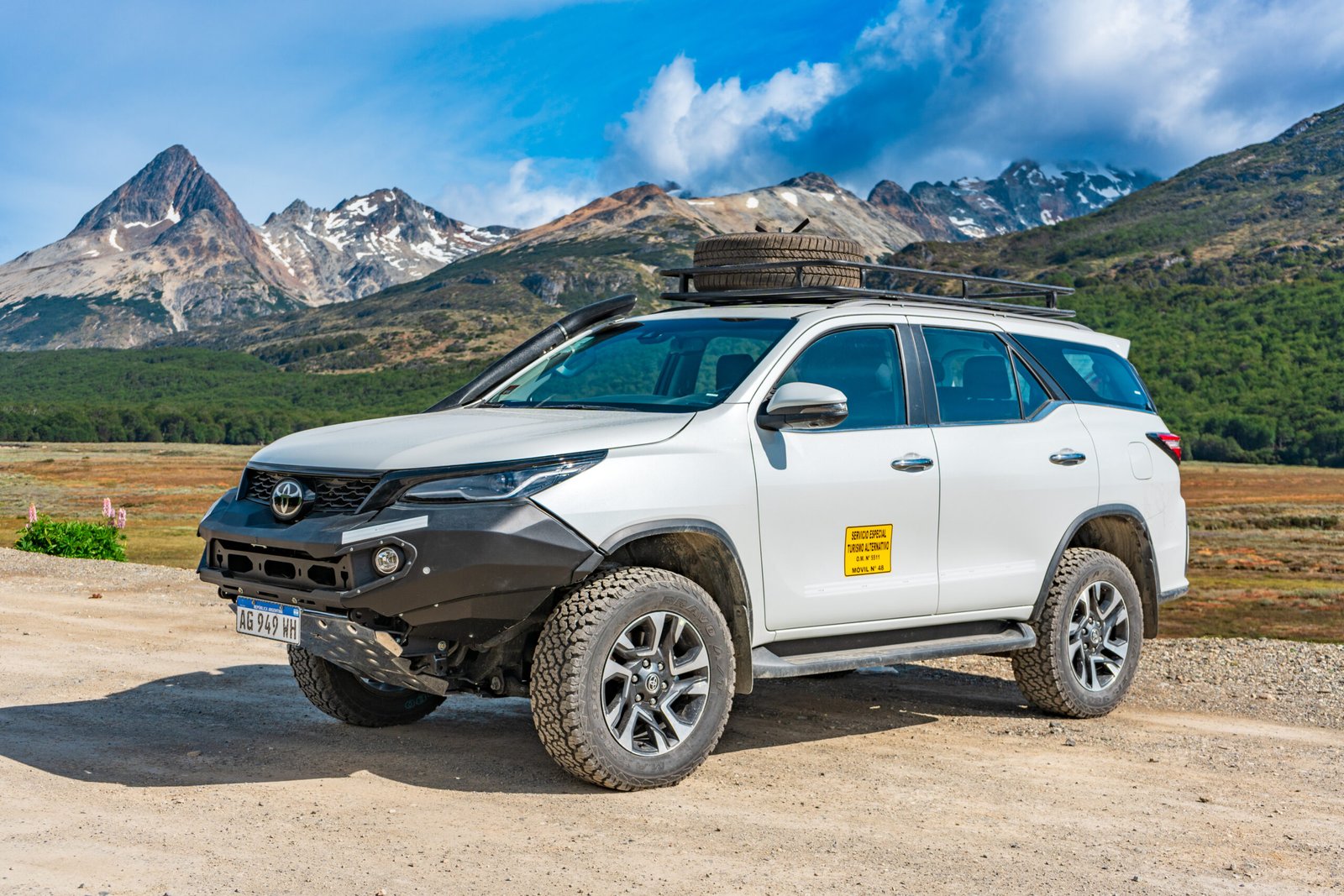 Camioneta 4x4 blanca estacionada en el Valle de Tierra Mayor con montañas nevadas al fondo en Tierra del Fuego.