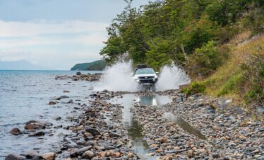 Camioneta 4x4 cruzando un camino junto al lago en una travesía off road en Tierra del Fuego