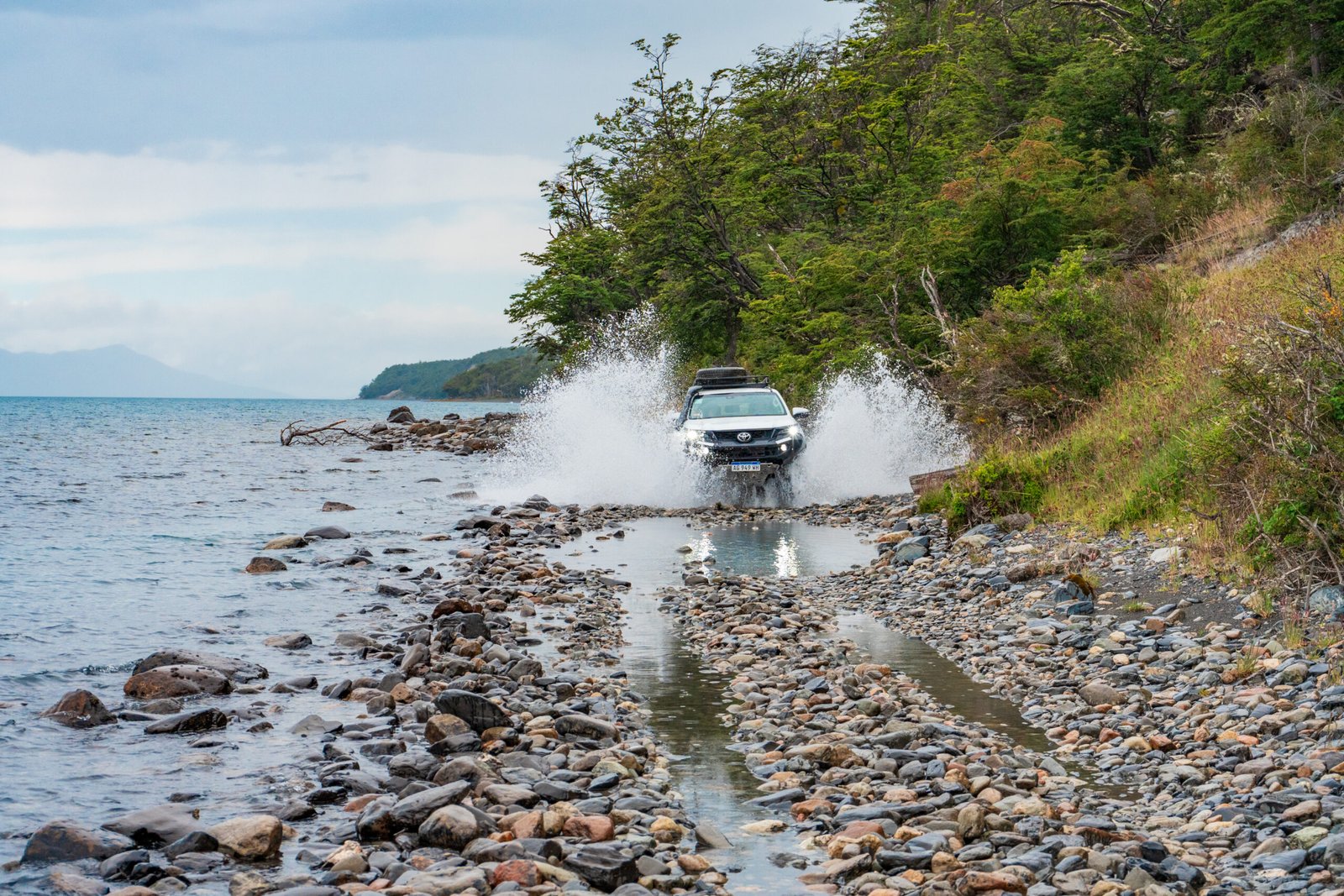 Camioneta 4x4 cruzando un camino junto al lago en una travesía off road en Tierra del Fuego