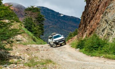 Camioneta 4x4 avanzando por un camino de montaña rocoso en Tierra del Fuego rodeado de naturaleza y montañas.