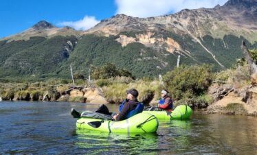 Dos turistas navegando en balsas de packrafting por las aguas cristalinas del Río Olivia, con la Cordillera de los Andes de fondo en Ushuaia. Excursión de Vértice Expediciones.
