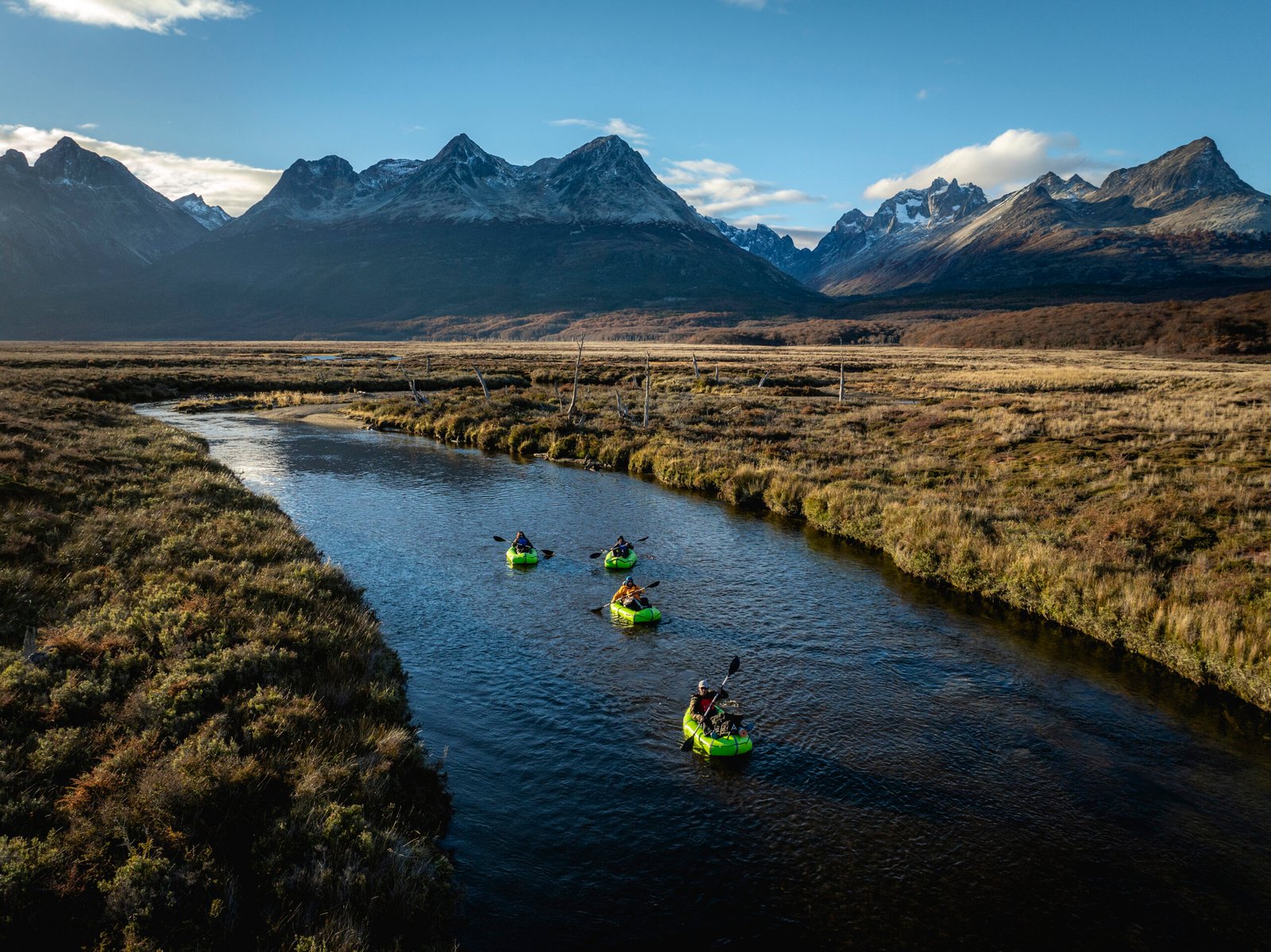 Grupo de personas navegando en packraft por el río olivia rodeado de montañas y un paisaje natural de la Patagonia bajo un cielo despejado - Vértice Expediciones