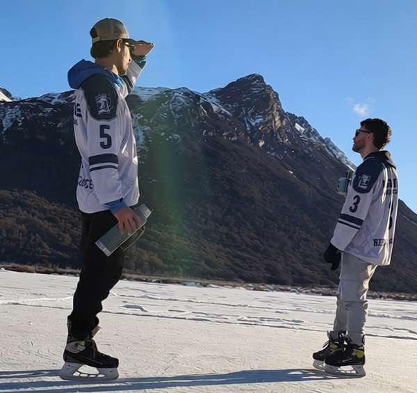 Dos patinadores en una laguna congelada de Ushuaia junto al guía Marcelo Vaca de Vértice Expediciones, con la cordillera de Tierra del Fuego de fondo y palos de hockey en primer plano.