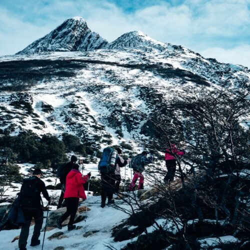 Fila de senderistas subiendo una ladera nevada rumbo a Laguna Esmeralda guiados por Marcelo Vaca de VERTICE Expediciones.