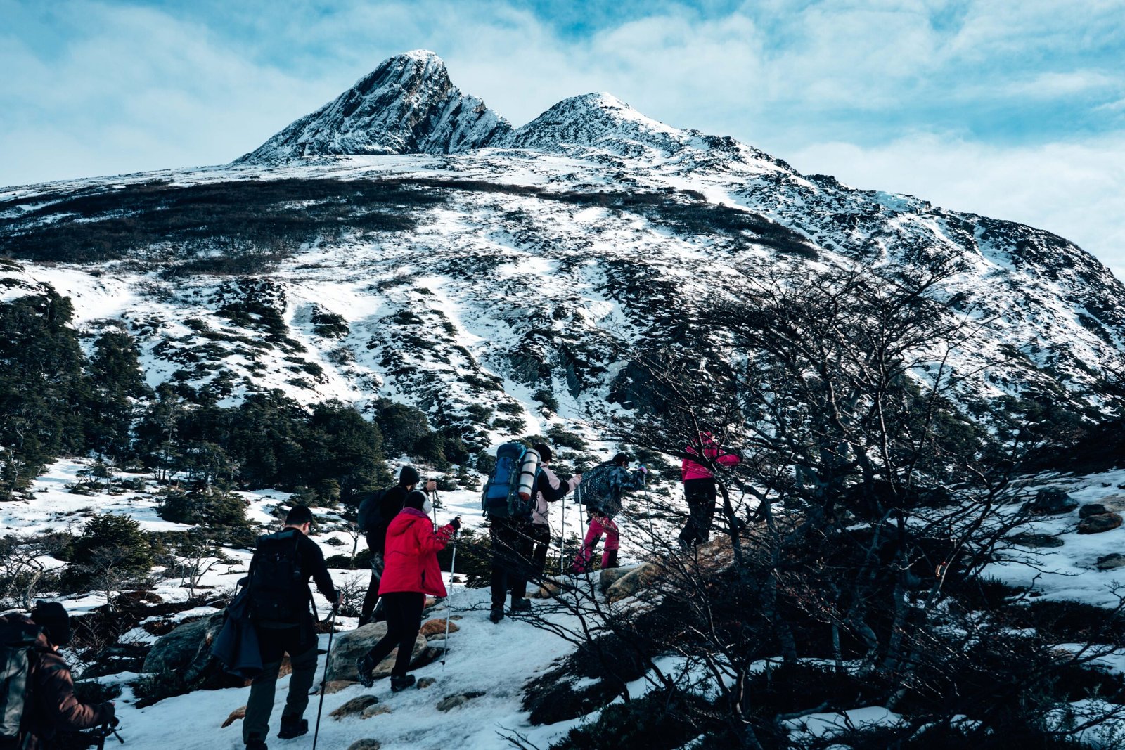 Fila de senderistas subiendo una ladera nevada rumbo a Laguna Esmeralda guiados por Marcelo Vaca de VERTICE Expediciones.