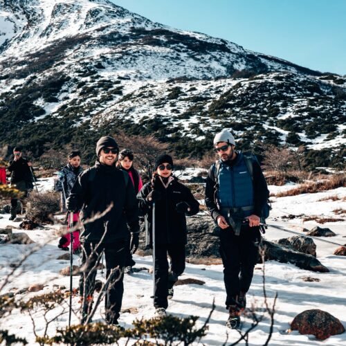 Grupo guiado por VERTICE caminando con bastones y ropa de abrigo por sendero nevado hacia Laguna Esmeralda Ushuaia